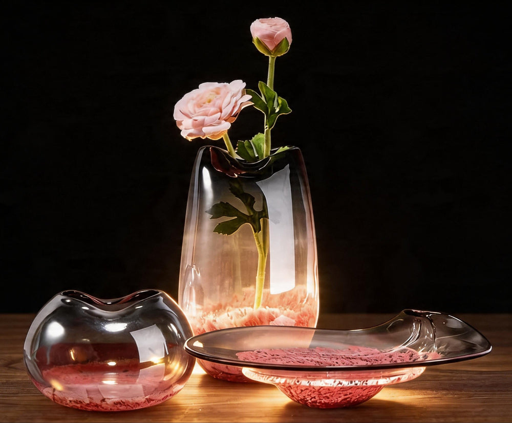 Two luxury glass vases with flowers on a wooden surface against a dark background