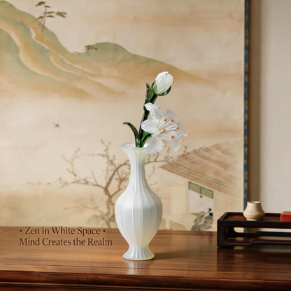 White vase with crystal glass flowers on a wooden table in front of a scenic wall painting.