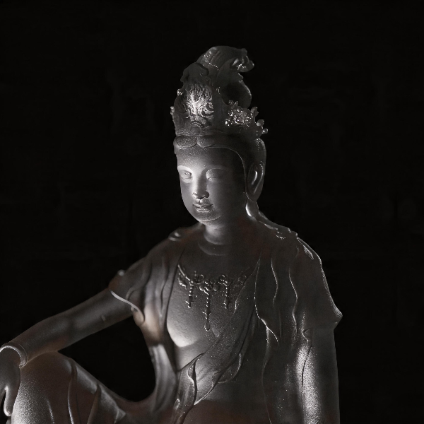Statue of a seated figure with intricate details on a dark background