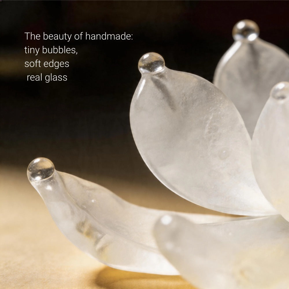Close-up of a translucent glass flower with soft edges and tiny bubbles, set against a dark background.