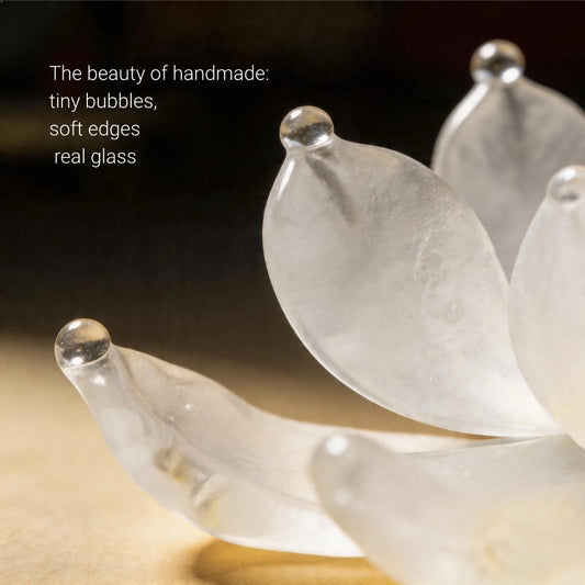 Close-up of a translucent glass flower with soft edges and tiny bubbles, set against a dark background.